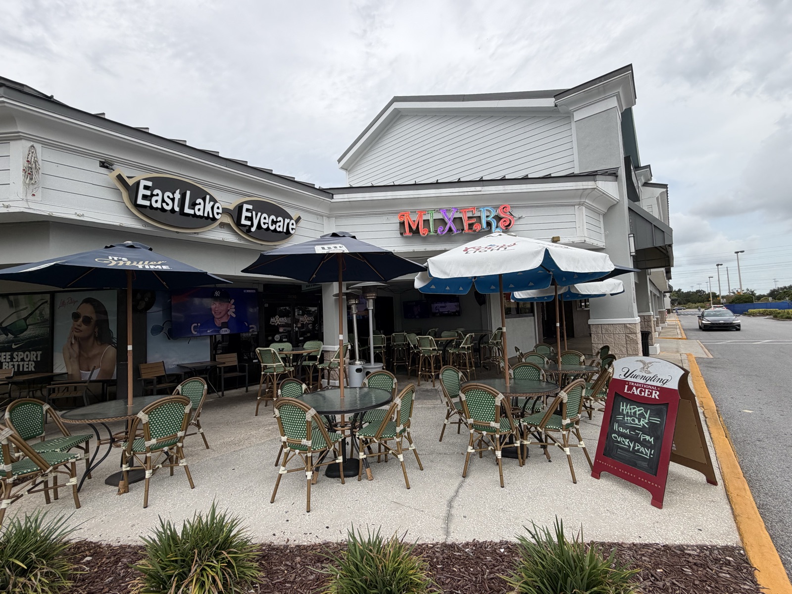The covered patio at Mixers Bar & Grill in Palm Harbor — umbrellas, bistro seating, and the neon Mixers sign